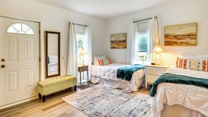 A bedroom with two beds, a bench, a bedside table, a mirror, and artwork on the walls. - Lakeview Vacation Rental - Walk to Crystal Lake! (Lakeview)