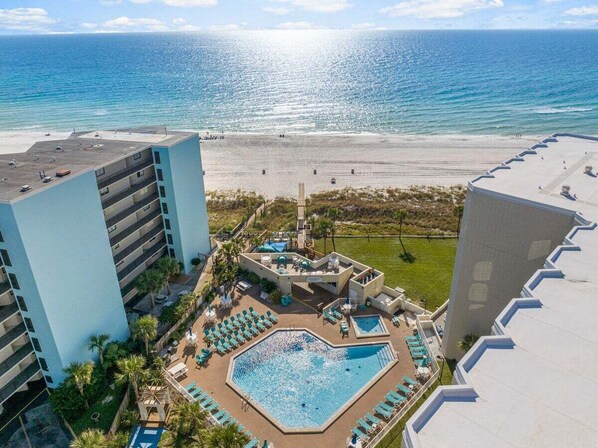 A hotel with a pool, lounge chairs, and a view of the beach and ocean.