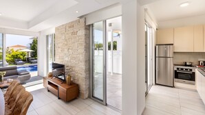 A modern living room with a stone wall, a TV, and a seating area. - 3 bedroom villa With Pool (Protaras)