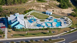 An aerial view of a resort with a large pool area, multiple water slides, and a parking lot. - Purple Pearl: Shared Pool with Lazy River (Kill Devil Hills)