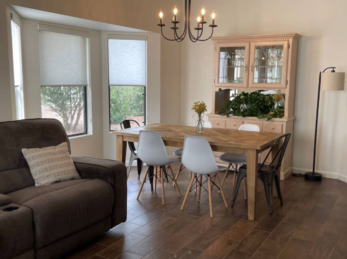Un comedor con una mesa y sillas de madera, un sofá acolchado y un aparador con puertas de vidrio.