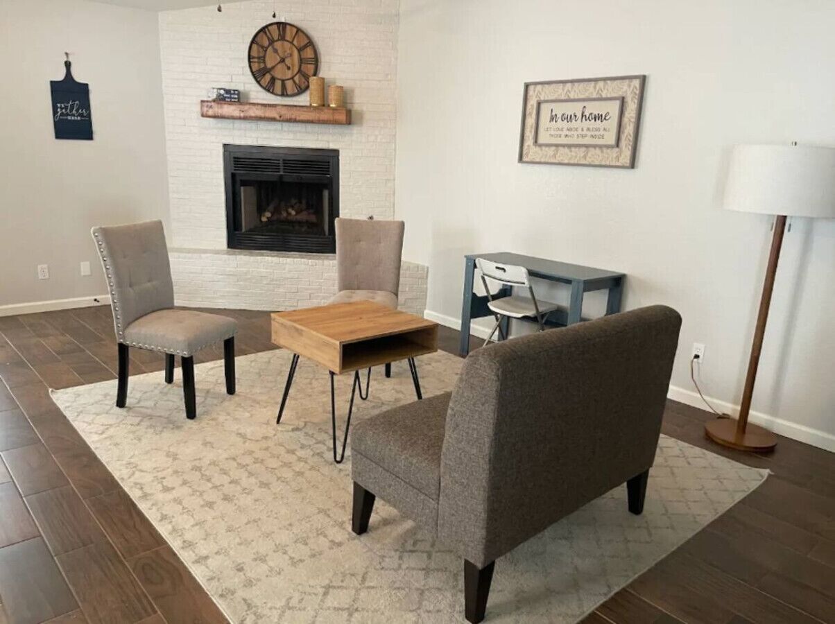 A living room with a fireplace, two armchairs, a coffee table, and a side table.
