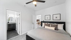 A bedroom with a bed, a ceiling fan, and framed pictures on the wall.