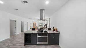 A modern kitchen with a central island, built-in oven, and stainless steel appliances.