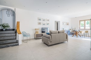 Una sala de estar moderna con un sofá, un televisor y un comedor con sillas y una mesa.