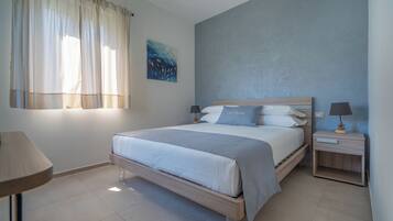 Un dormitorio moderno con cama, mesitas de noche y ventana con cortinas.