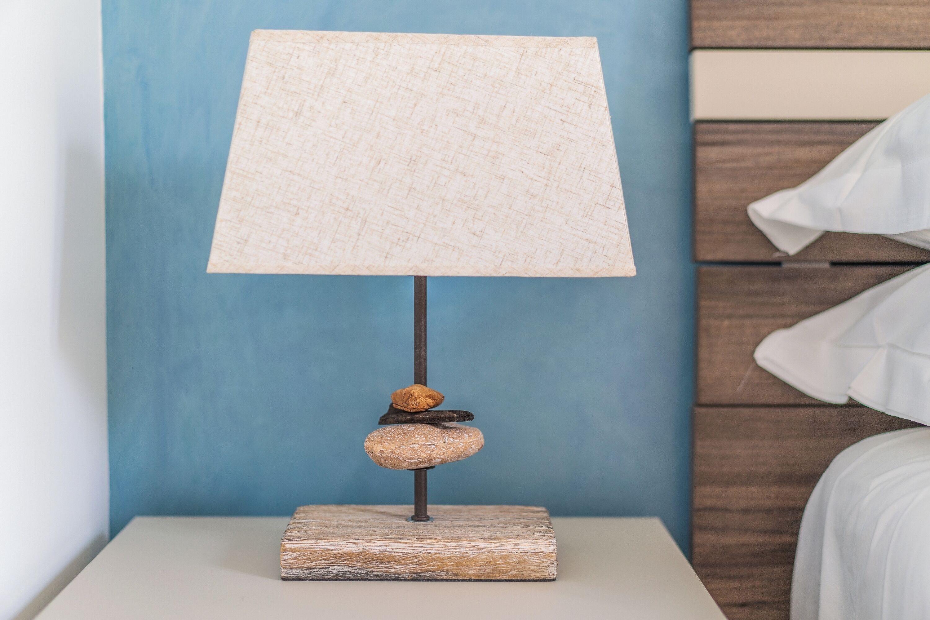 A bedside table with a lamp featuring a textured lampshade and a wooden base.