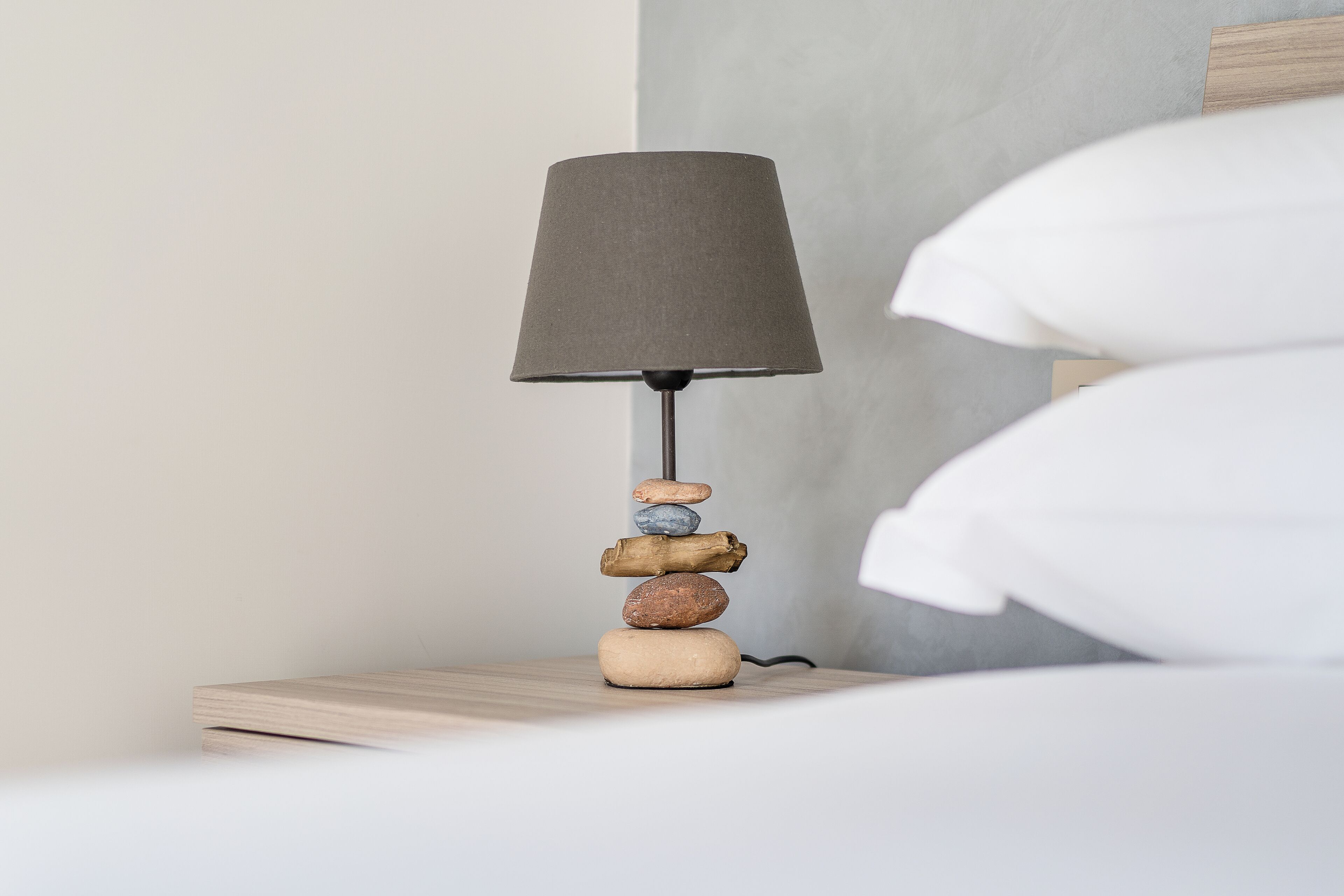 A bedside table with a lamp and a stack of stones.
