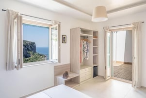 Un dormitorio con un ventanal grande, un armario y una cama.