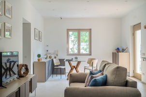 Una sala moderna con un sofá, una televisión y un comedor con sillas y una mesa.