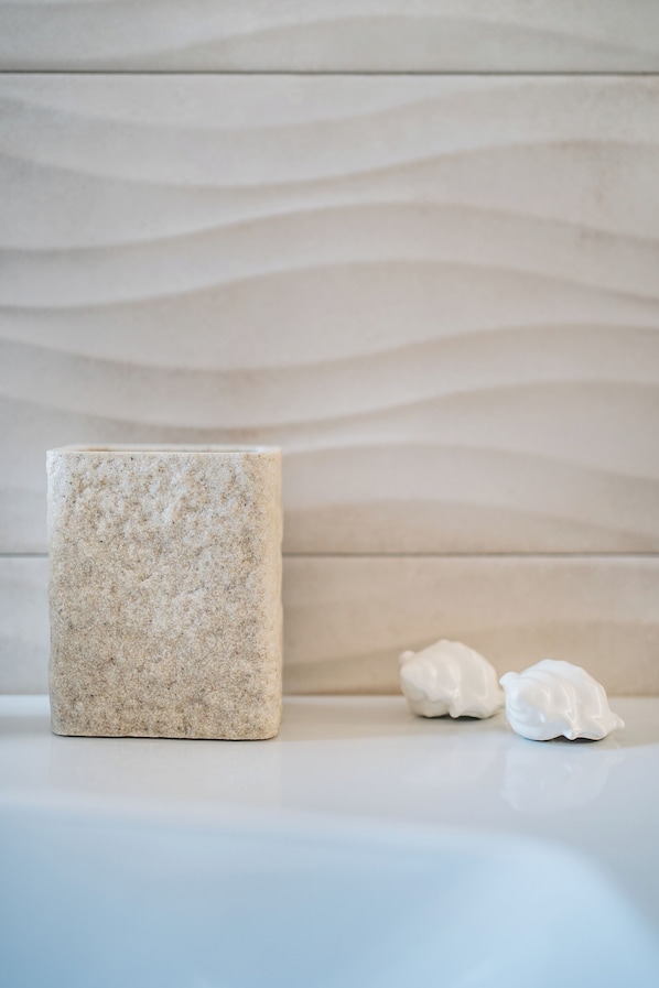 A bathroom with a large beige soap bar and two white soap sculptures on a white countertop.