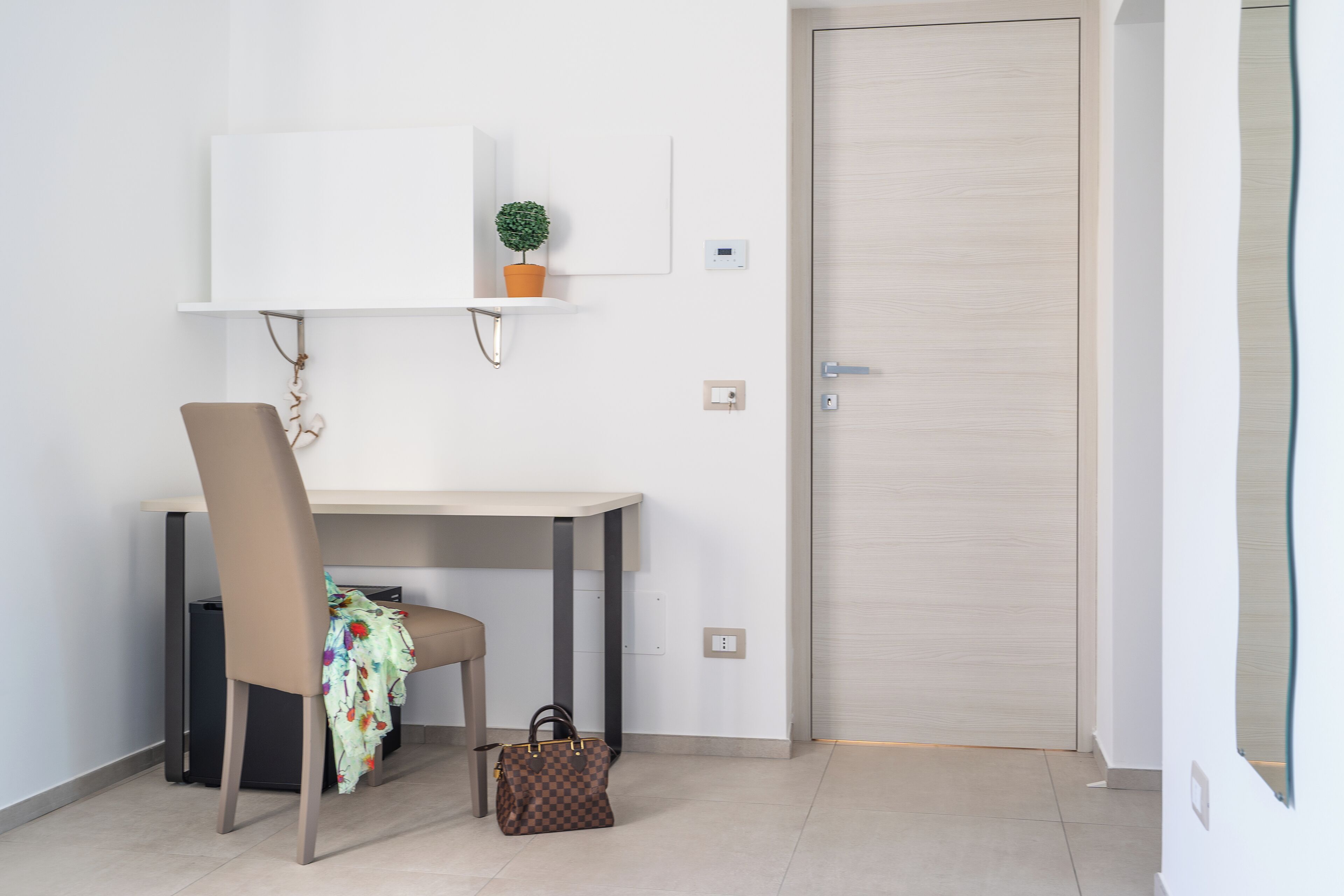Une petite pièce propre, avec un bureau, une chaise et une porte.