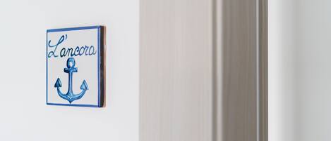 Une enseigne fixée au mur, portant le nom « Lancora » et le symbole d’une ancre.