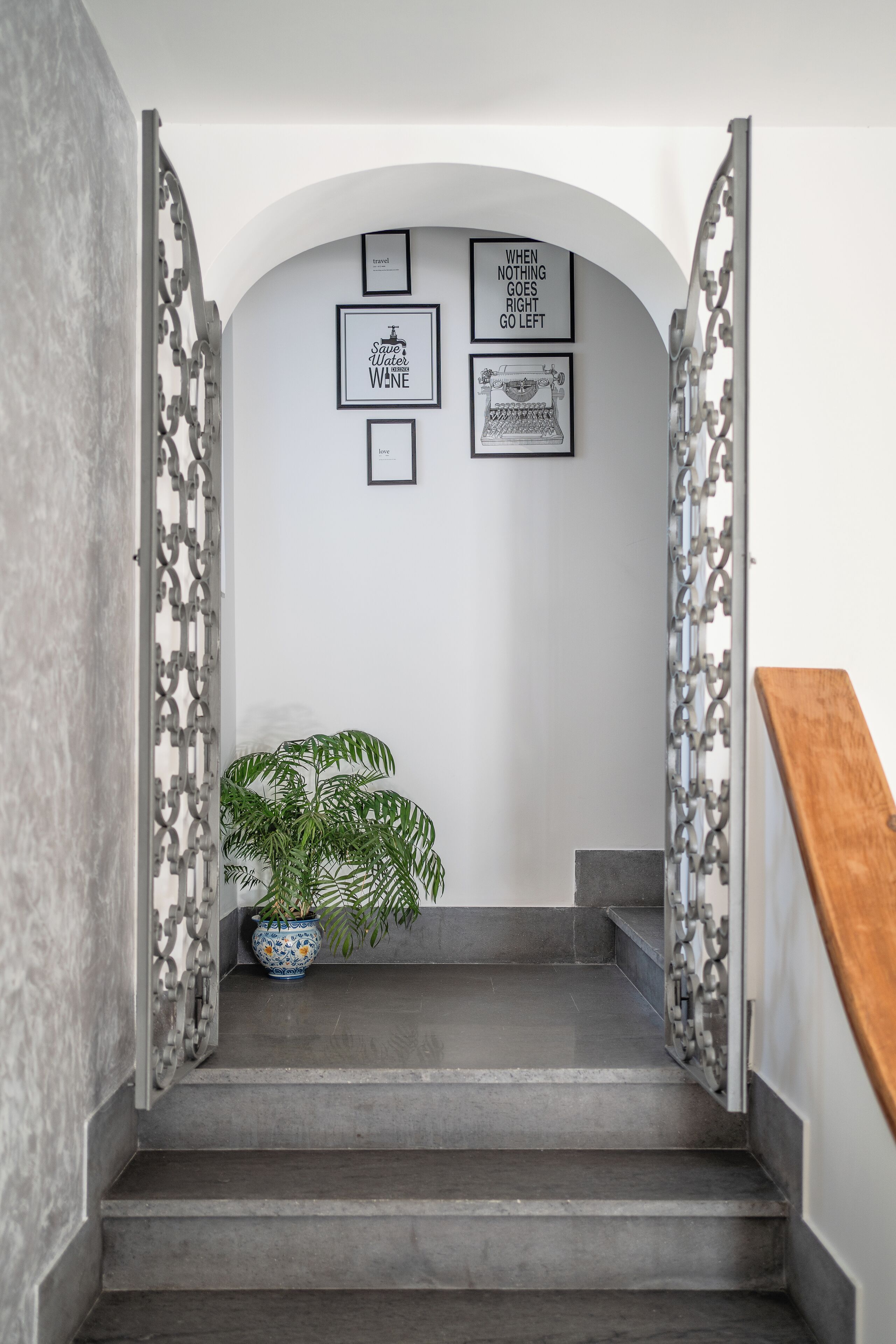 A staircase with a modern design, featuring a potted plant and framed inspirational quotes on the wall.