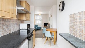 Une cuisine compacte avec des meubles en bois, un four encastré et un coin repas comprenant une table et des chaises.