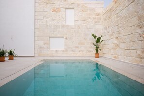 Una piscina con una pared de piedra y plantas en macetas.