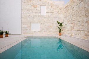 Una piscina con una pared de piedra y plantas en macetas.