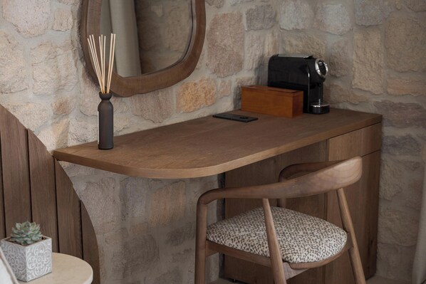A wooden desk with a mirror, a black coffee maker, and a smartphone. - Horizon Suites Milos (Milos)