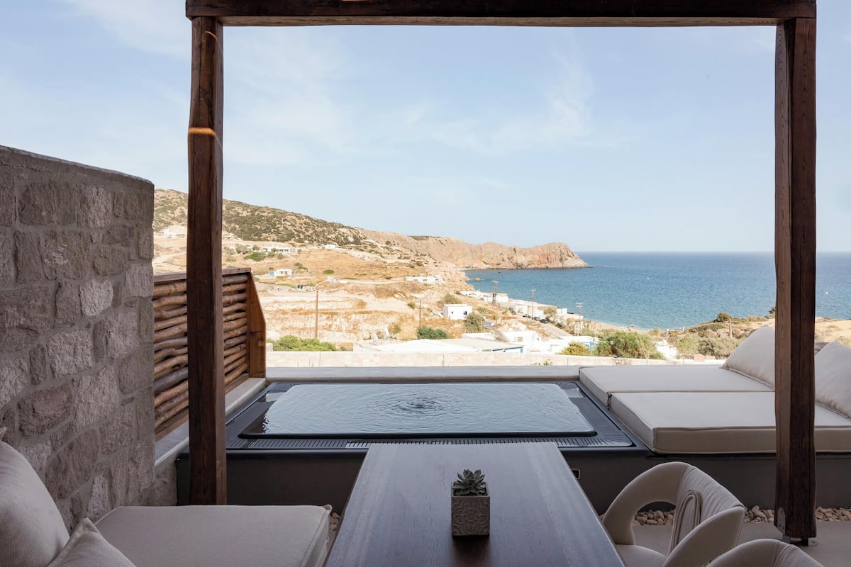 Ein Balkon mit Blick auf das Meer, einem Holztisch und einer Couch.