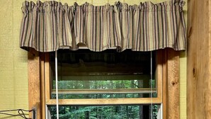 A kitchen with a double sink, a window with a view of a forest, and a bottle of hand soap on the counter. - Glady Hideaway (Bowden)