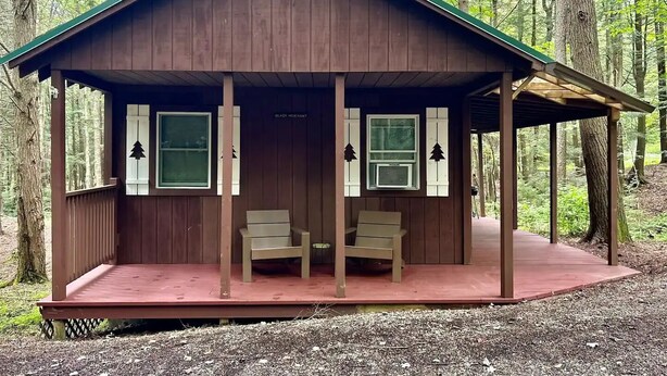 A cabin with a porch, two chairs, and a small table. - Glady Hideaway (Bowden)