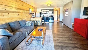 A modern living room with a sofa, coffee table, and kitchen in the background.