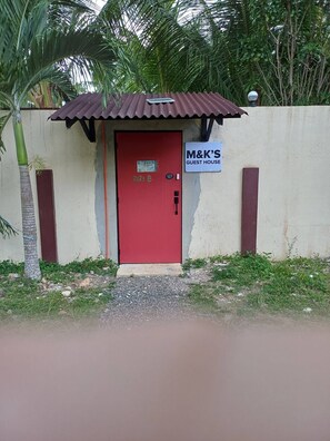 A small guest house with a red door, a sign indicating it's a guest house, and a corrugated metal roof. - Kubo A, Loft (M&K’s Guest House) (Dauis)