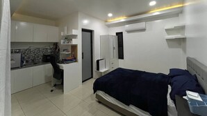 A compact bedroom with a bed, a small kitchenette, and a wardrobe.