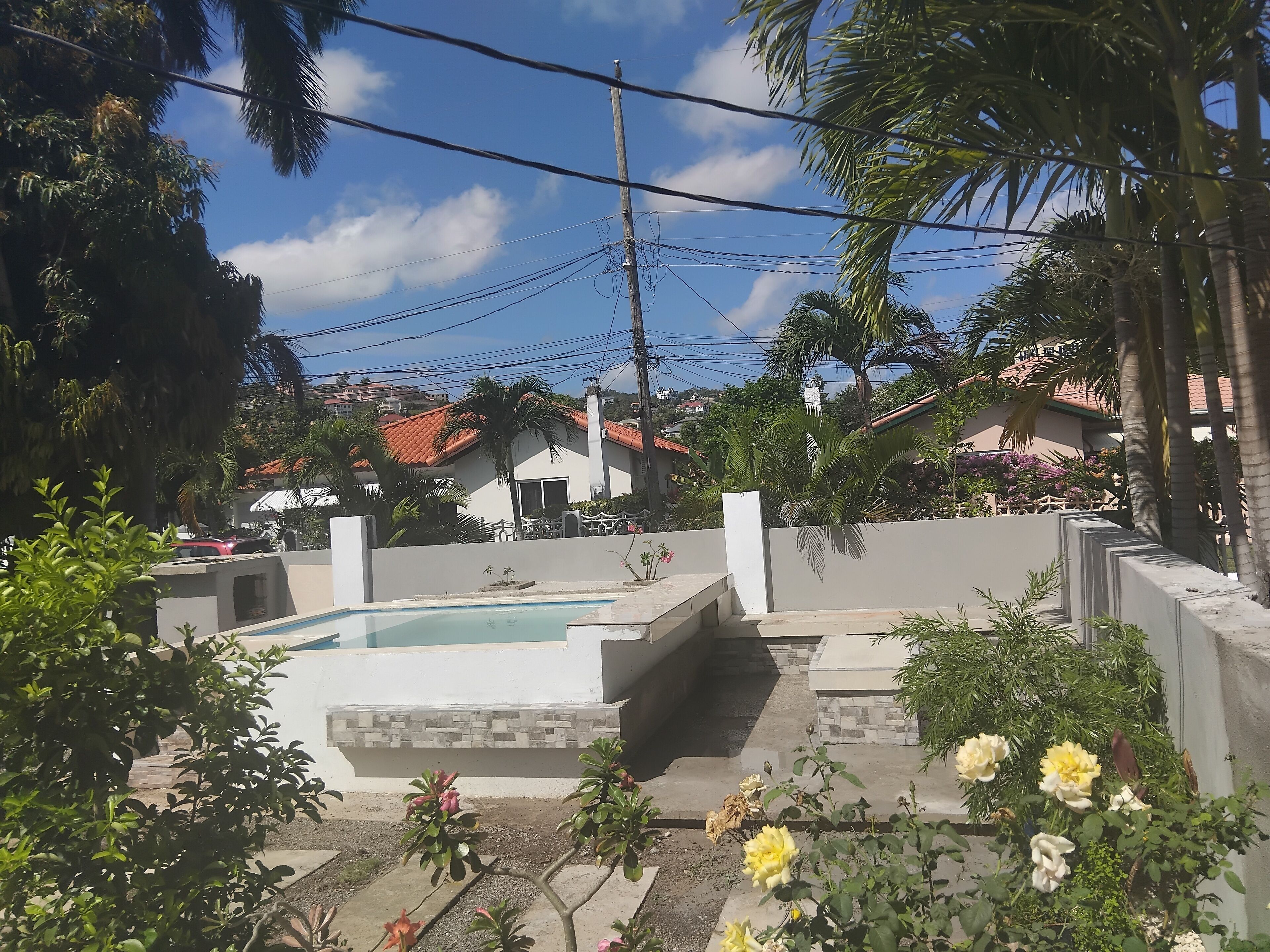 Una zona residencial con piscina, rodeada de vegetación y casas con tejados rojos.