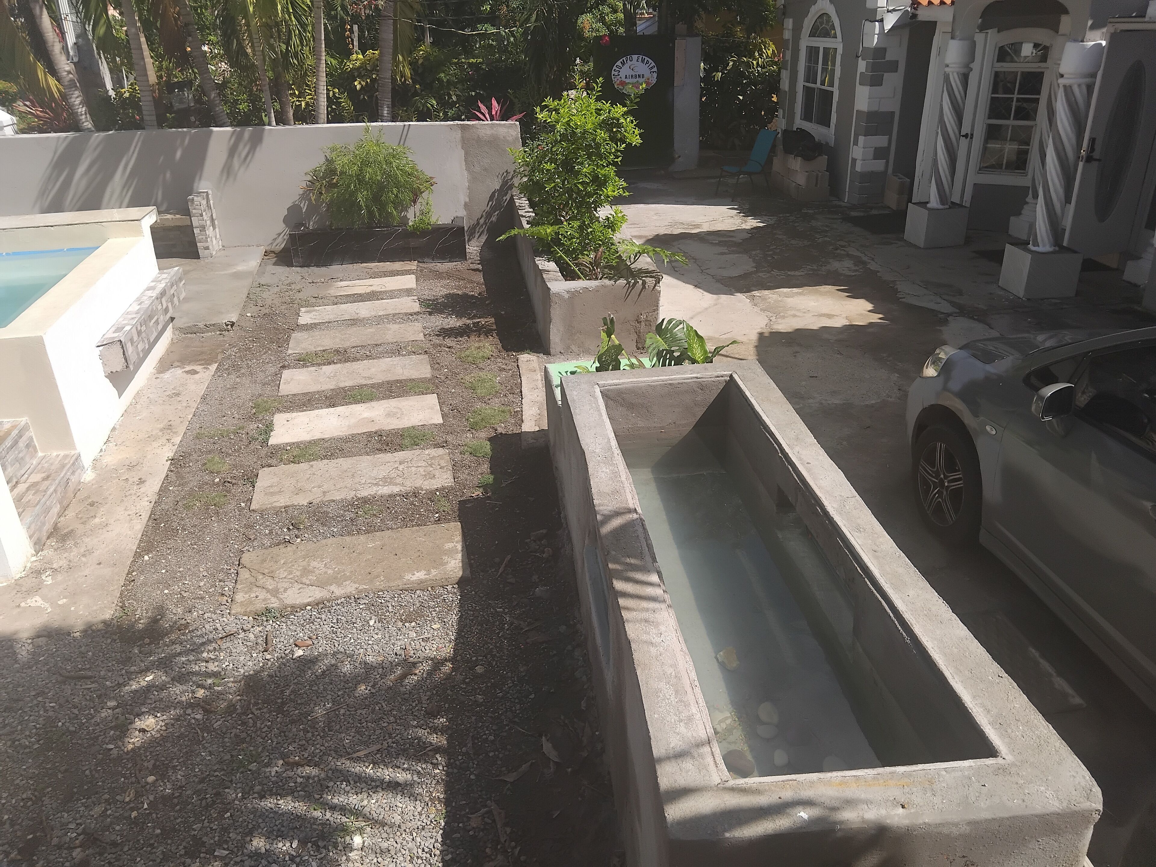 A courtyard with a swimming pool, concrete steps, and a parked car.