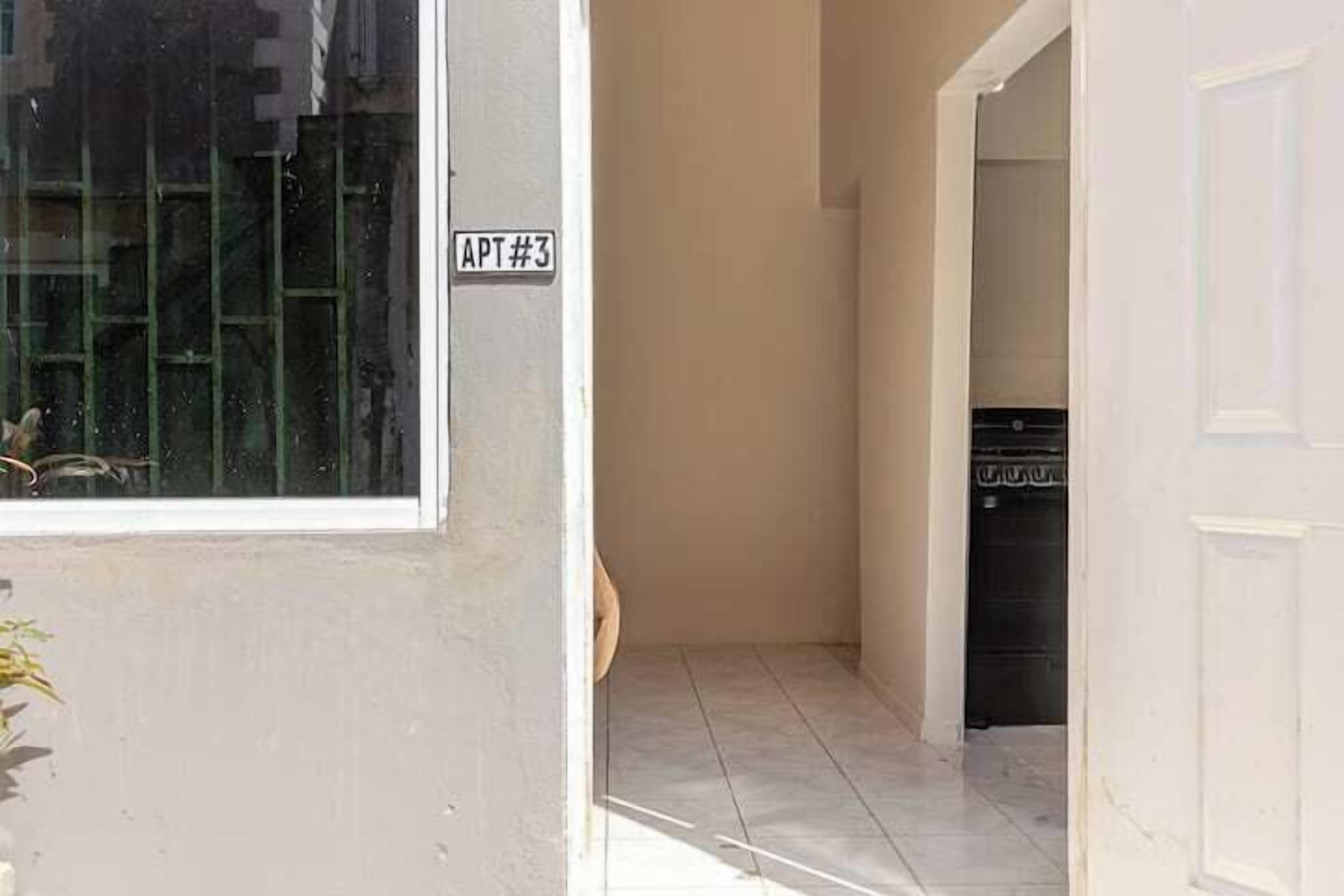 A hallway with a sign reading "APT#3" leading to a room with a black appliance.