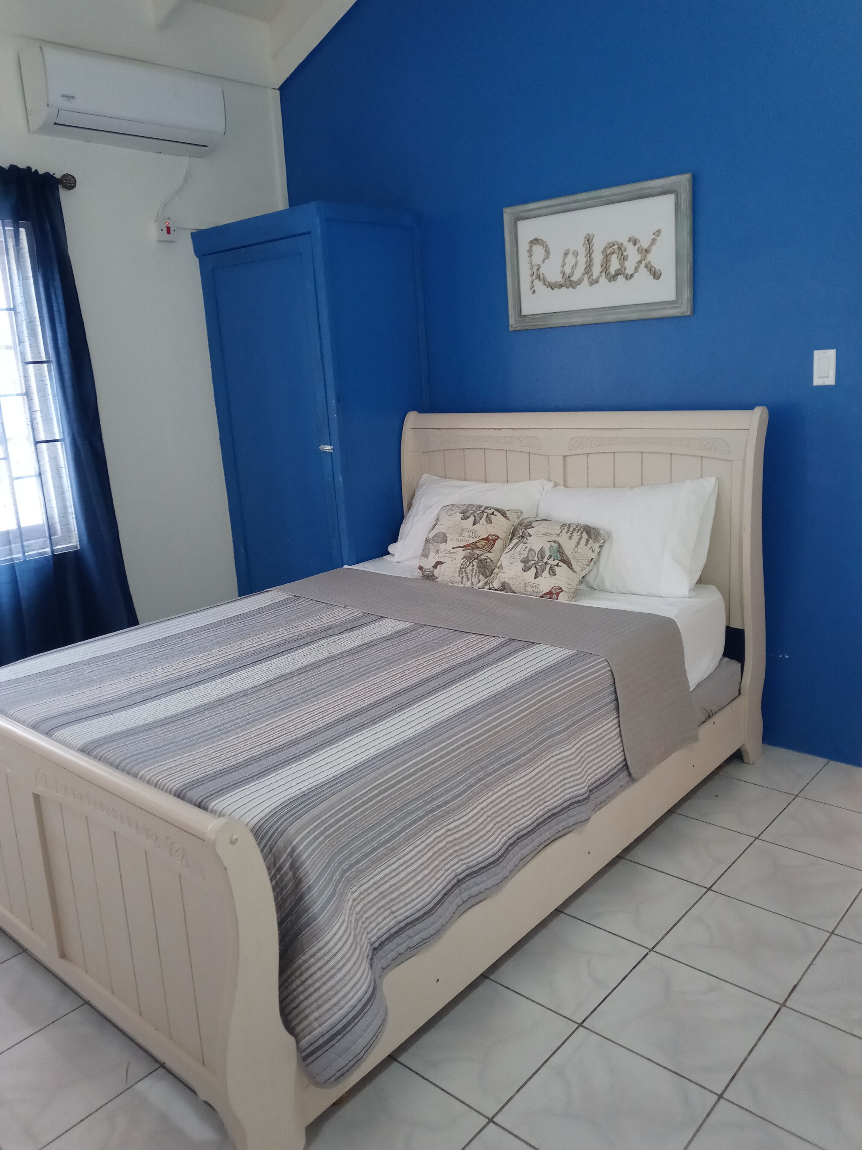 Un dormitorio con una cama, una pared azul y la palabra 'Relax' enmarcada en la pared.