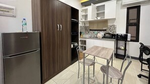 Une cuisine moderne équipée d’un réfrigérateur, de meubles de rangement en bois, d’une table à manger avec des chaises et d’un four à micro-ondes.