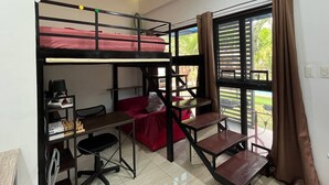 Une chambre de dortoir avec des lits superposés, un bureau et une chaise.