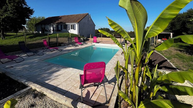 A swimming pool with lounge chairs, a house, and a garden with banana plants. - House 10 People Swimming Pool With Jacuzzi (Boucé)