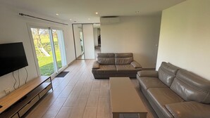 A spacious living room with a large sofa, a coffee table, and a flat-screen TV. - House 10 People Swimming Pool With Jacuzzi (Boucé)