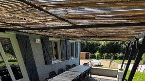 An outdoor patio area with a barbecue grill, a long table with chairs, and a covered seating area. - House 10 People Swimming Pool With Jacuzzi (Boucé)