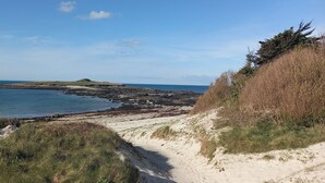 A coastal landscape with a sandy path leading to a rocky shoreline. - Gîte L'escale Portsallaise (Ploudalmézeau)