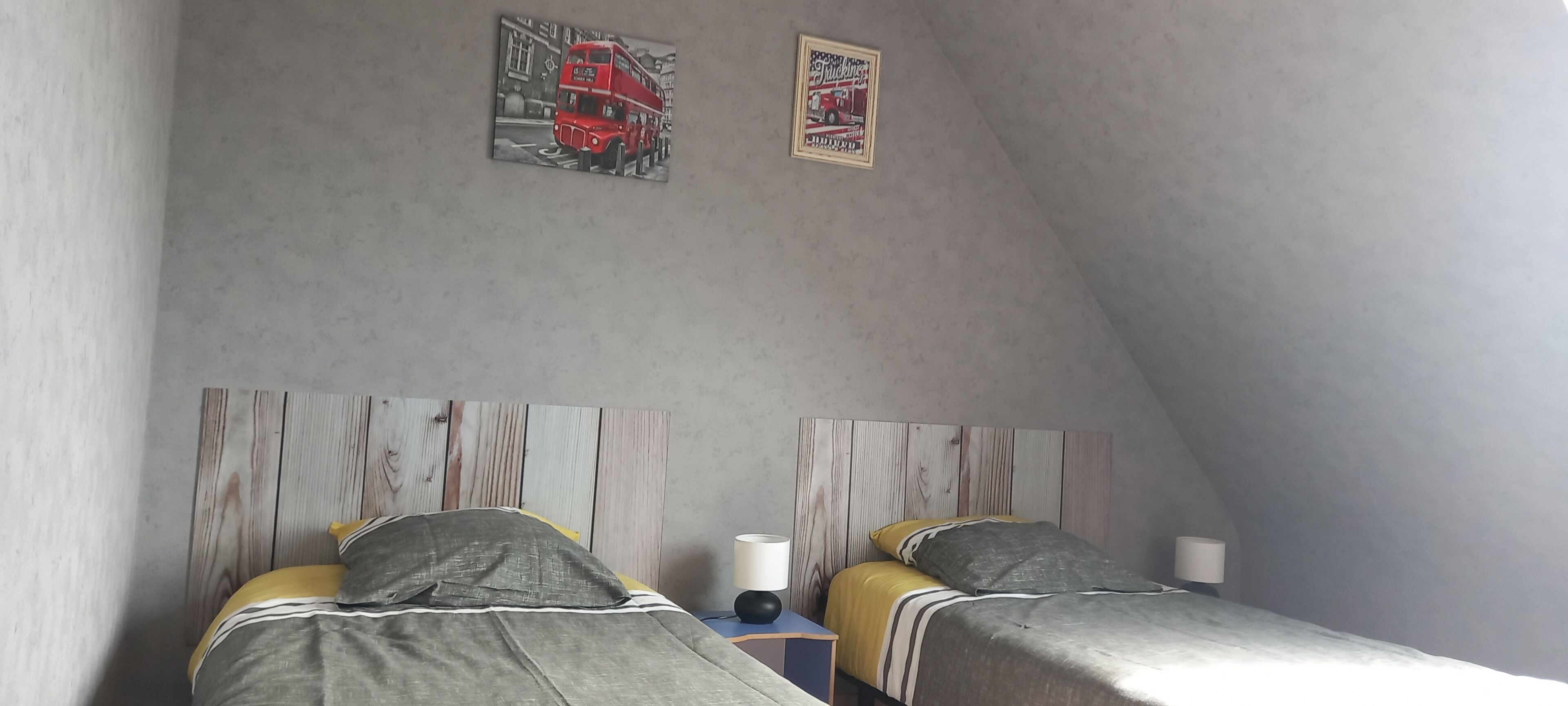 Una habitación con dos camas, cabeceros de madera y dos cuadros en la pared.
