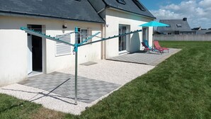 A house with a patio area, a clothesline, and a small garden. - Gîte L'escale Portsallaise (Ploudalmézeau)