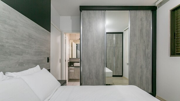 Een moderne hotelkamer met een groot bed, een garderobe en een badkamer door een open deur zichtbaar.