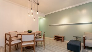 Een moderne eetruimte met een houten tafel en stoelen, een klein bijzettafeltje en een zwart poef.