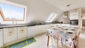 Una cocina moderna con tragaluces, armarios blancos y un comedor con mesa para cuatro.