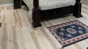 Una cama con dosel de cuatro columnas con acabado oscuro, un ventilador de techo y dos lámparas de noche.