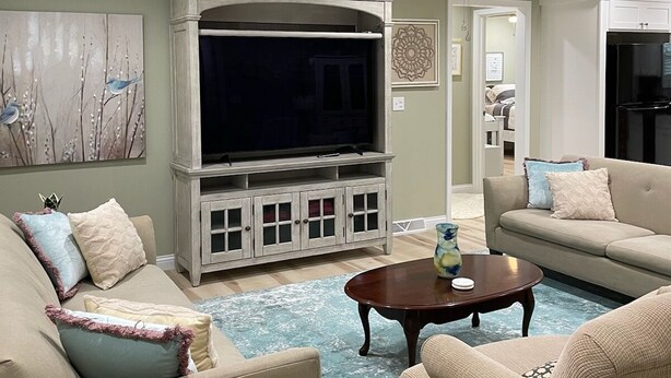 Una sala de estar con una televisión de pantalla plana grande, un ventilador de techo y un sofá.