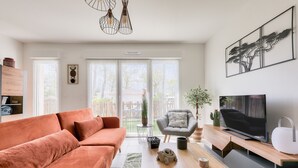 Una sala de estar moderna con un sofá, una mesa de centro, un televisor y una planta.