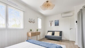 Un dormitorio con una cama grande, un escritorio, un sofá y una ventana con persianas.
