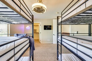 Ein Zimmer mit Etagenbetten, einem Deckenventilator, einem Fernseher und einer Tür zu einem anderen Raum.
