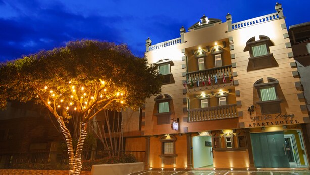 Un hotel de estilo arquitectónico tradicional, con varios balcones y una entrada bien iluminada.