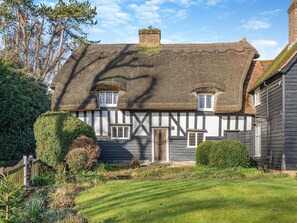 A traditional half-timbered house with a thatched roof, a wooden gate, and a well-maintained garden. - 2 bedroom accommodation in Much Hadham (Much Hadham)